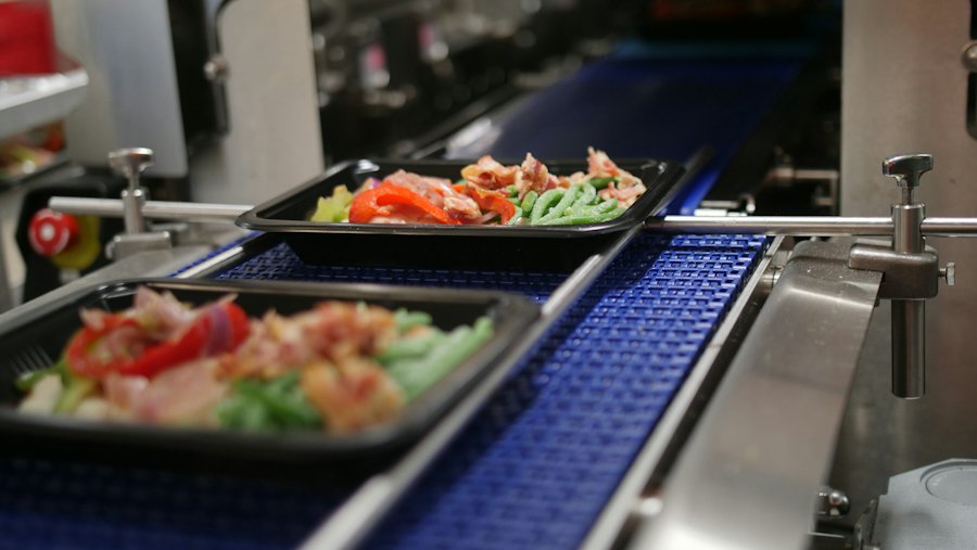 Barquettes de plats préparés sur un convoyeur de ligne alimentaire